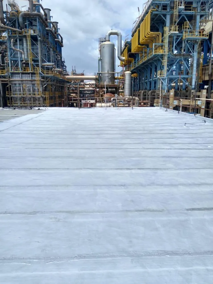 Vista amplia de techo impermeabilizado con planta industrial al fondo